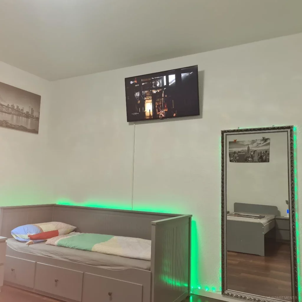 Schlafbereich mit Einzelbett und Spiegel – Apartment 5 in Bochum