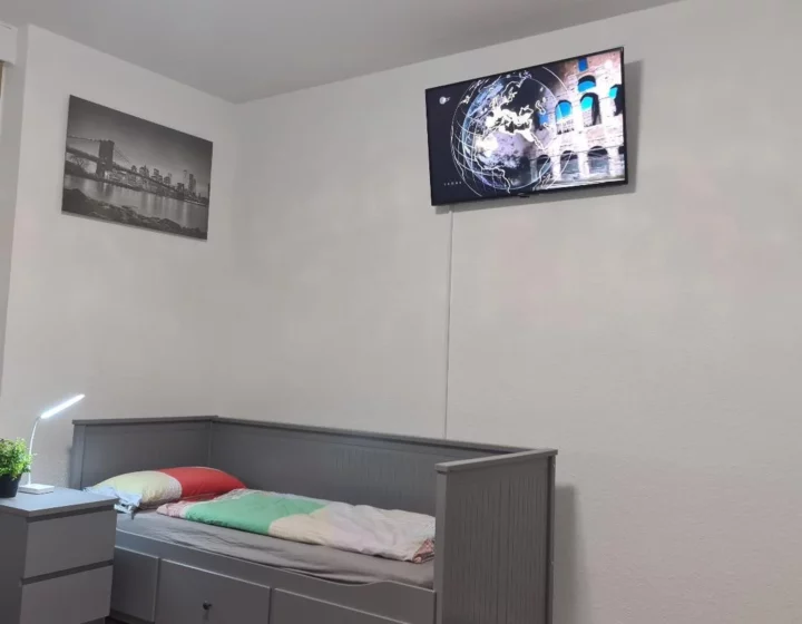 Einzelbett und Fernseher im Zimmer – Apartment 5 in Bochum