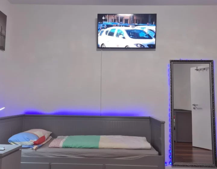 Schlafbereich mit Fernseher und farbiger Beleuchtung – Apartment 5 in Bochum