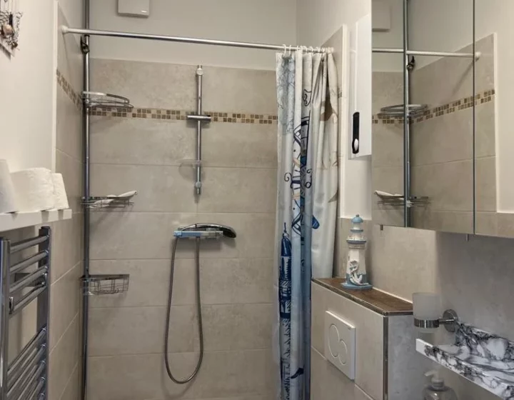 Dusche, Waschbecken und Spiegel im Badezimmer – Apartment 5 in Bochum
