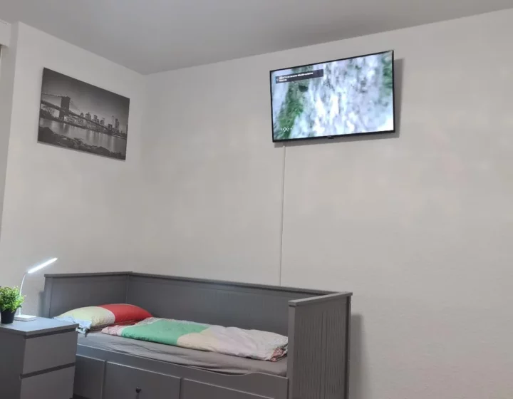 Schlafbereich mit Fenster und Fernseher – Apartment 5 in Bochum