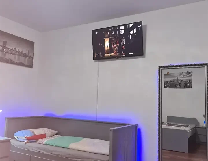 Einzelbett mit farbiger Beleuchtung – Apartment 5 in Bochum